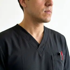 Delantal Madrid Hero Negro – detalle del cuello en V y bolsillo Delantal clínico Madrid Hero color Negro, detalle del cuello en V y bolsillo, uniforme antifluidos para hombre